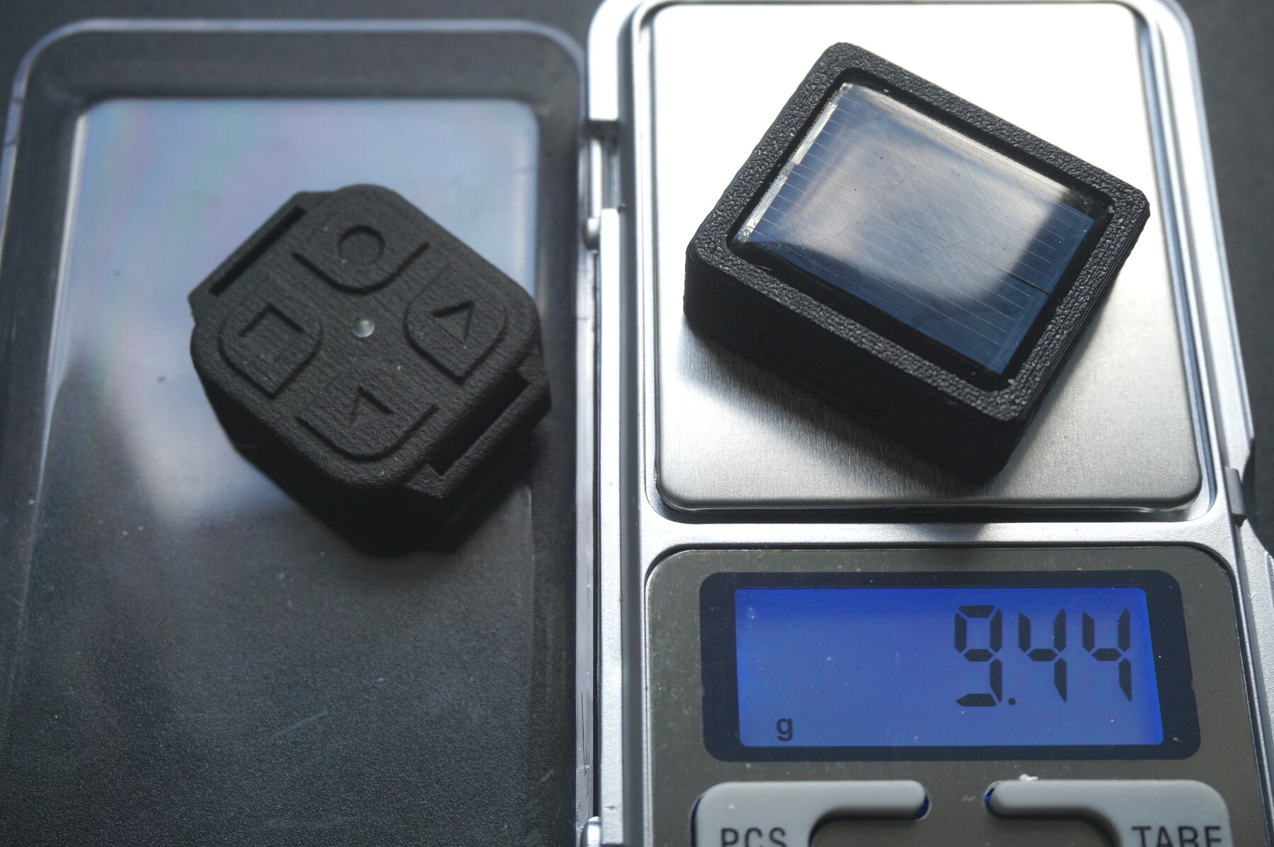 The complete SunVario on a jeweller's scale, next to a FlyBeeper remote
